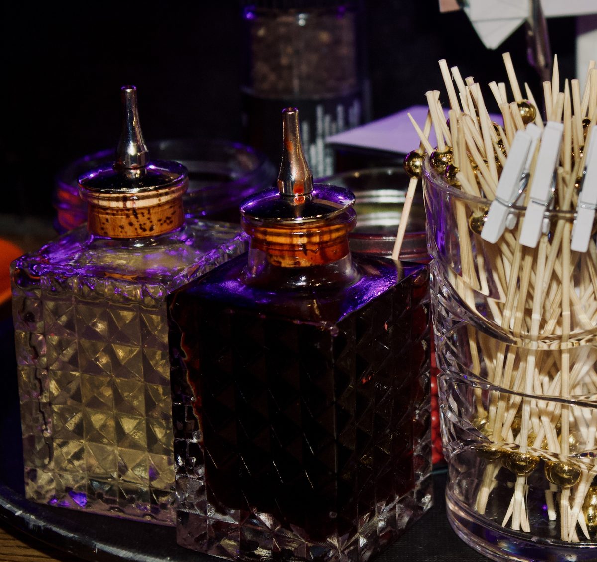 Cut-glass bitters bottles and garnish picks on the bar
