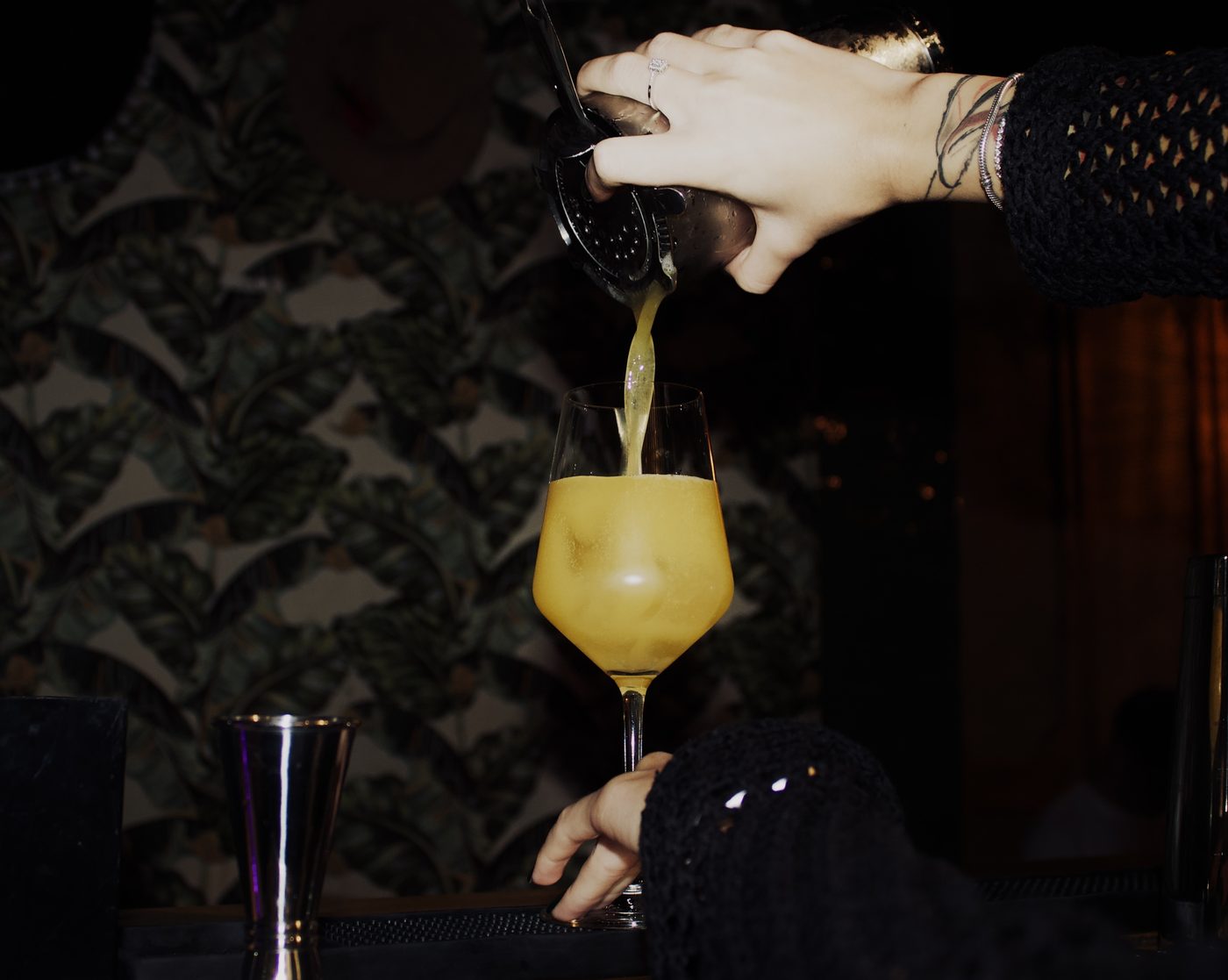 A bartender straining a cocktail into a glass